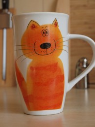 Katinas ant puodelio, skirto pienui gerti